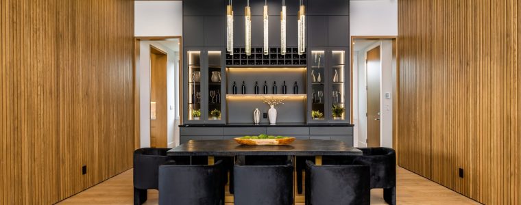 Modern dining room with black chairs, wooden walls, and a stylish chandelier, showcasing a contemporary interior design.